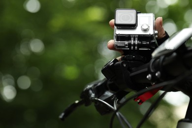 Man with modern action camera on bicycle outdoors, closeup. Space for text