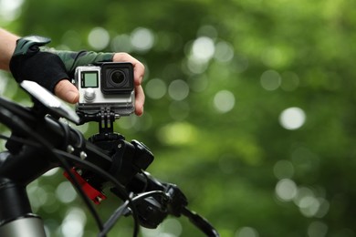 Photo of Man with modern action camera on bicycle outdoors, closeup. Space for text