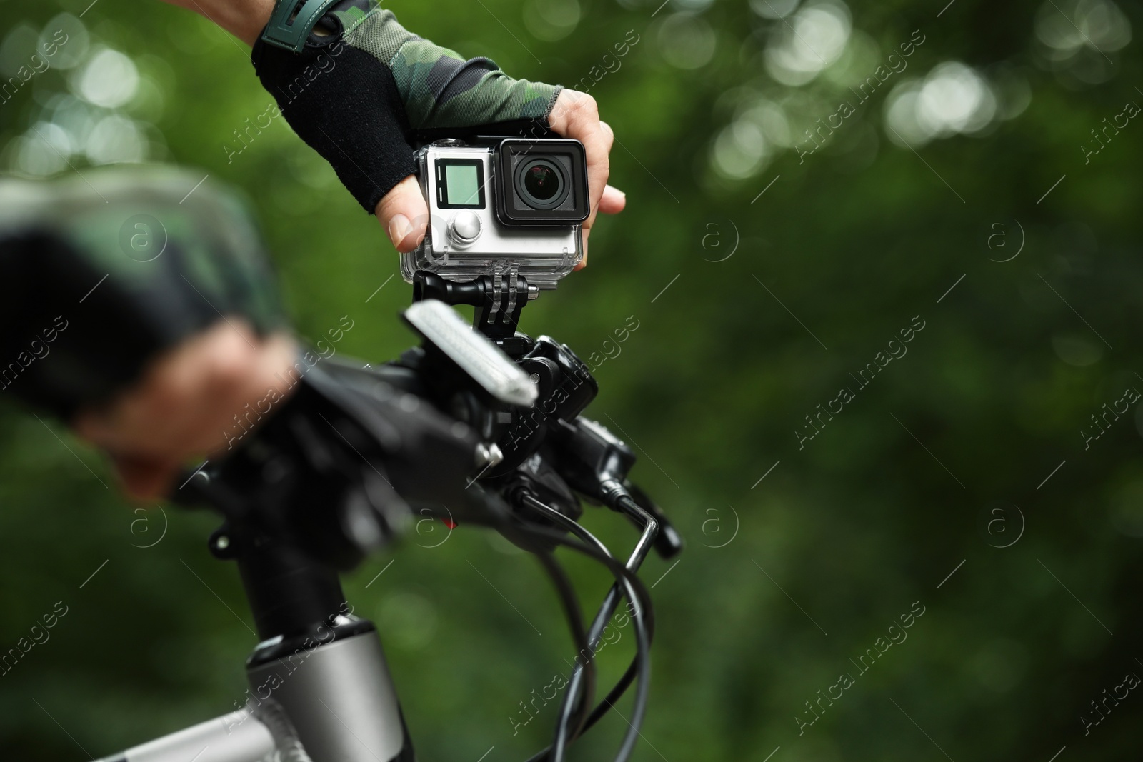 Photo of Man with modern action camera on bicycle outdoors, closeup. Space for text