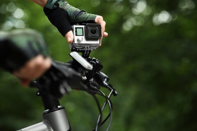 Photo of Man with modern action camera on bicycle outdoors, closeup. Space for text