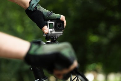 Photo of Man with modern action camera on bicycle outdoors, closeup. Space for text