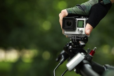 Man with modern action camera on bicycle outdoors, closeup. Space for text