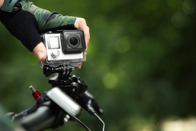 Man with modern action camera on bicycle outdoors, closeup. Space for text