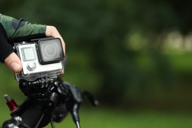 Man with modern action camera on bicycle outdoors, closeup. Space for text