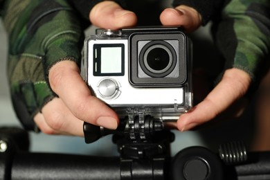 Photo of Man with modern action camera on bicycle outdoors, closeup