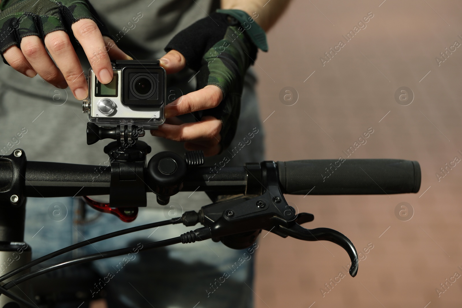 Photo of Man with modern action camera on bicycle outdoors, closeup. Space for text