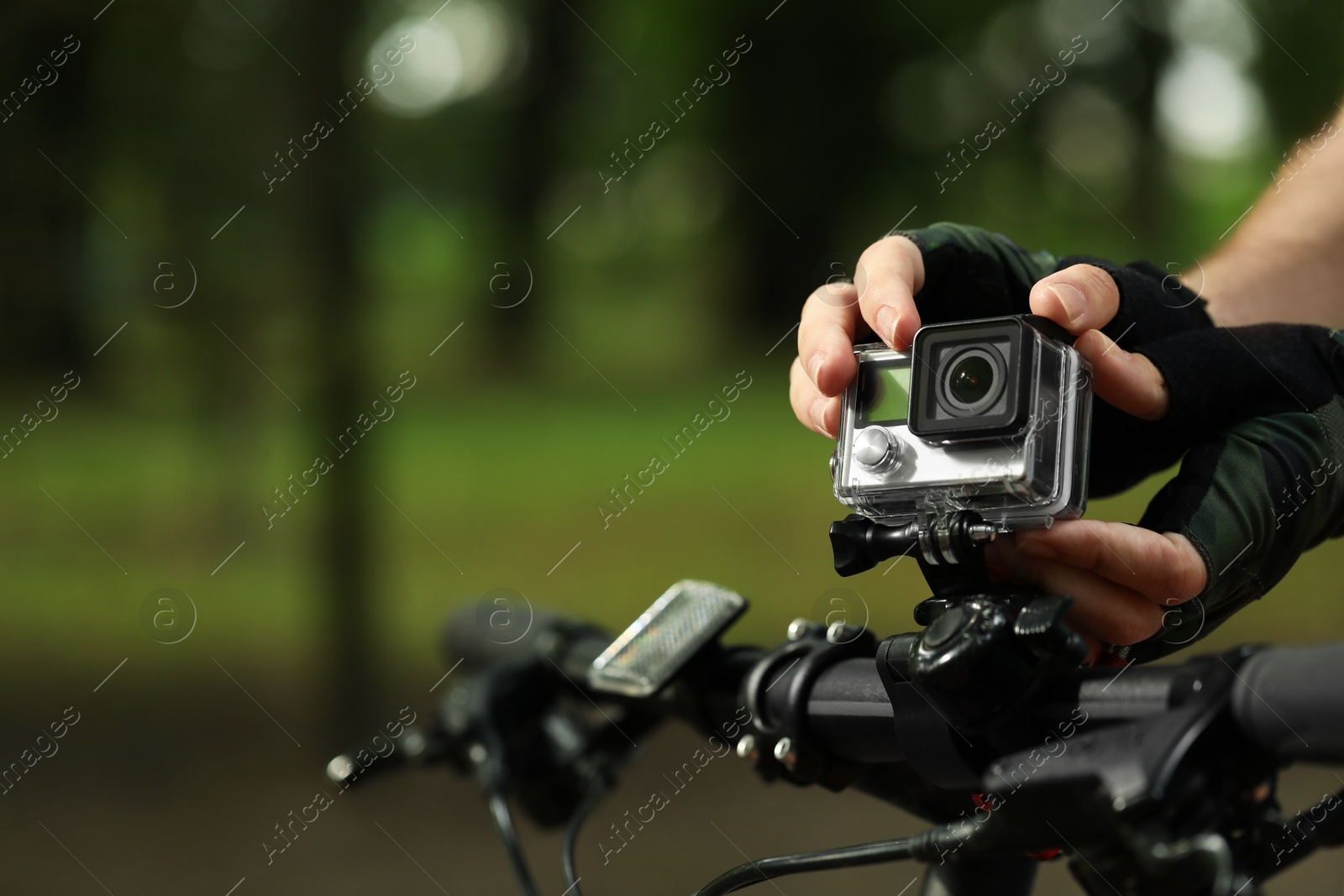 Photo of Man with modern action camera on bicycle outdoors, closeup. Space for text