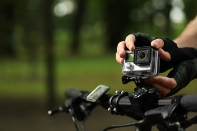 Photo of Man with modern action camera on bicycle outdoors, closeup. Space for text