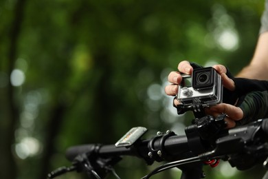 Photo of Man with modern action camera on bicycle outdoors, closeup. Space for text