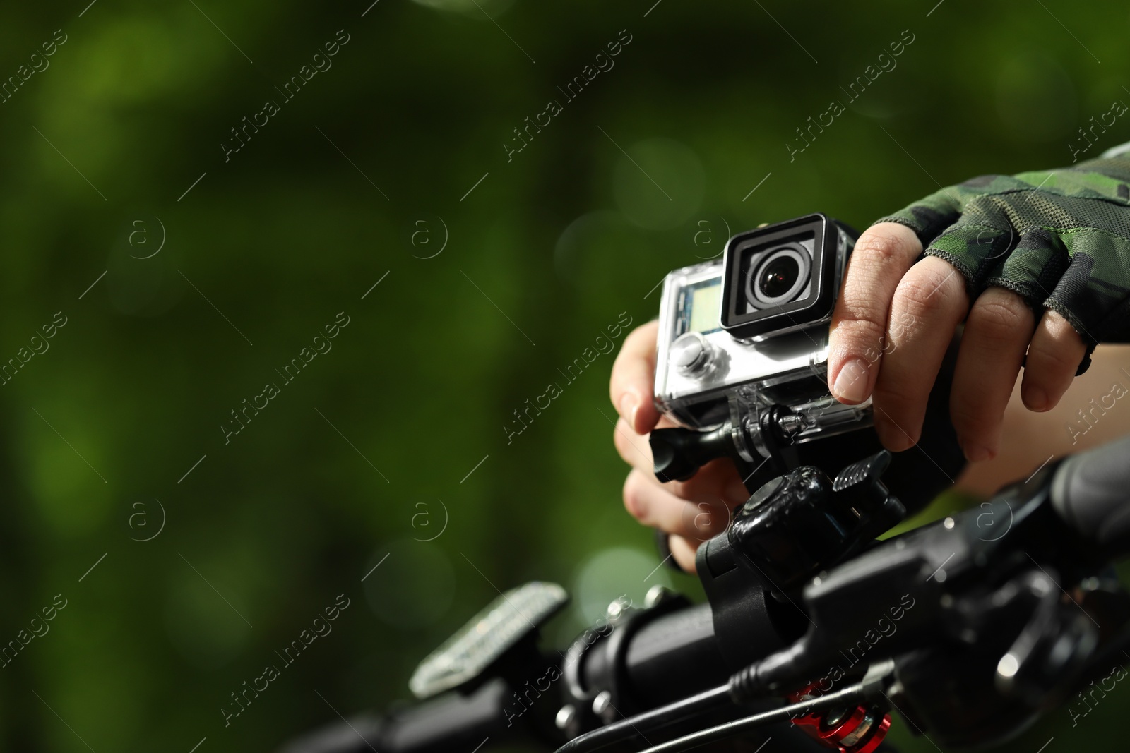 Photo of Man with modern action camera on bicycle outdoors, closeup. Space for text