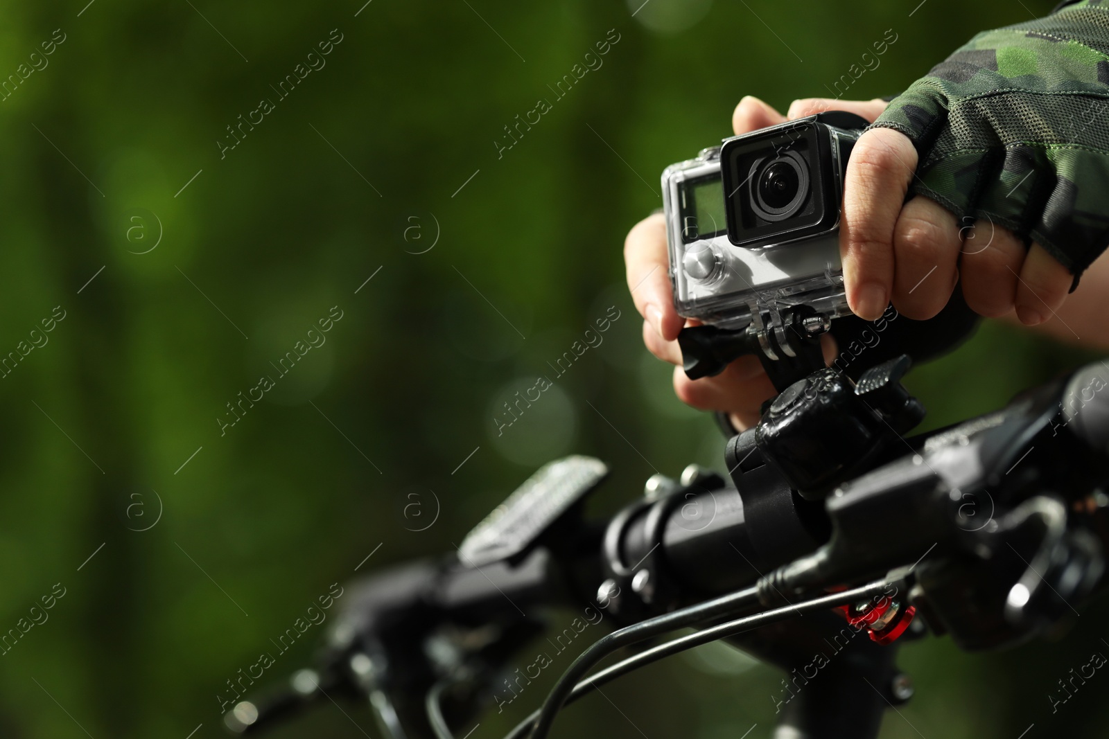 Photo of Man with modern action camera on bicycle outdoors, closeup. Space for text