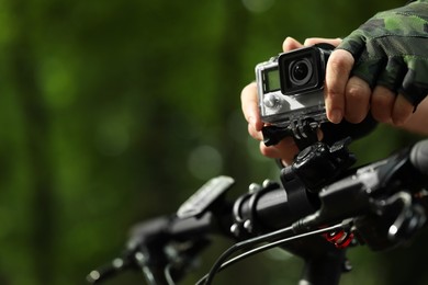 Photo of Man with modern action camera on bicycle outdoors, closeup. Space for text