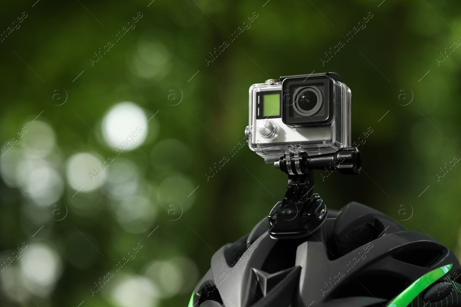 Photo of Modern action camera with mount on helmet outdoors, closeup. Space for text