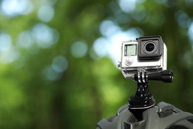 Modern action camera with mount on helmet outdoors, closeup. Space for text