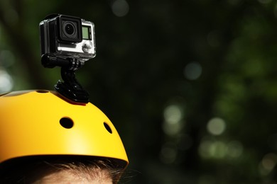 Man with modern action camera on helmet outdoors, closeup. Space for text