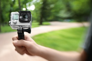 Photo of Man using modern action camera outdoors, closeup