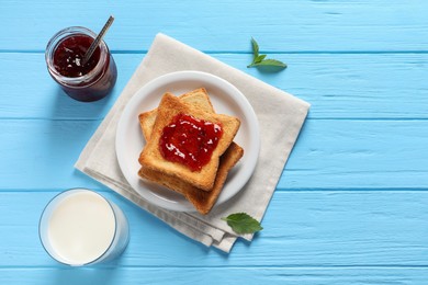 Photo of Delicious toasts with jam and milk on light blue wooden table, flat lay