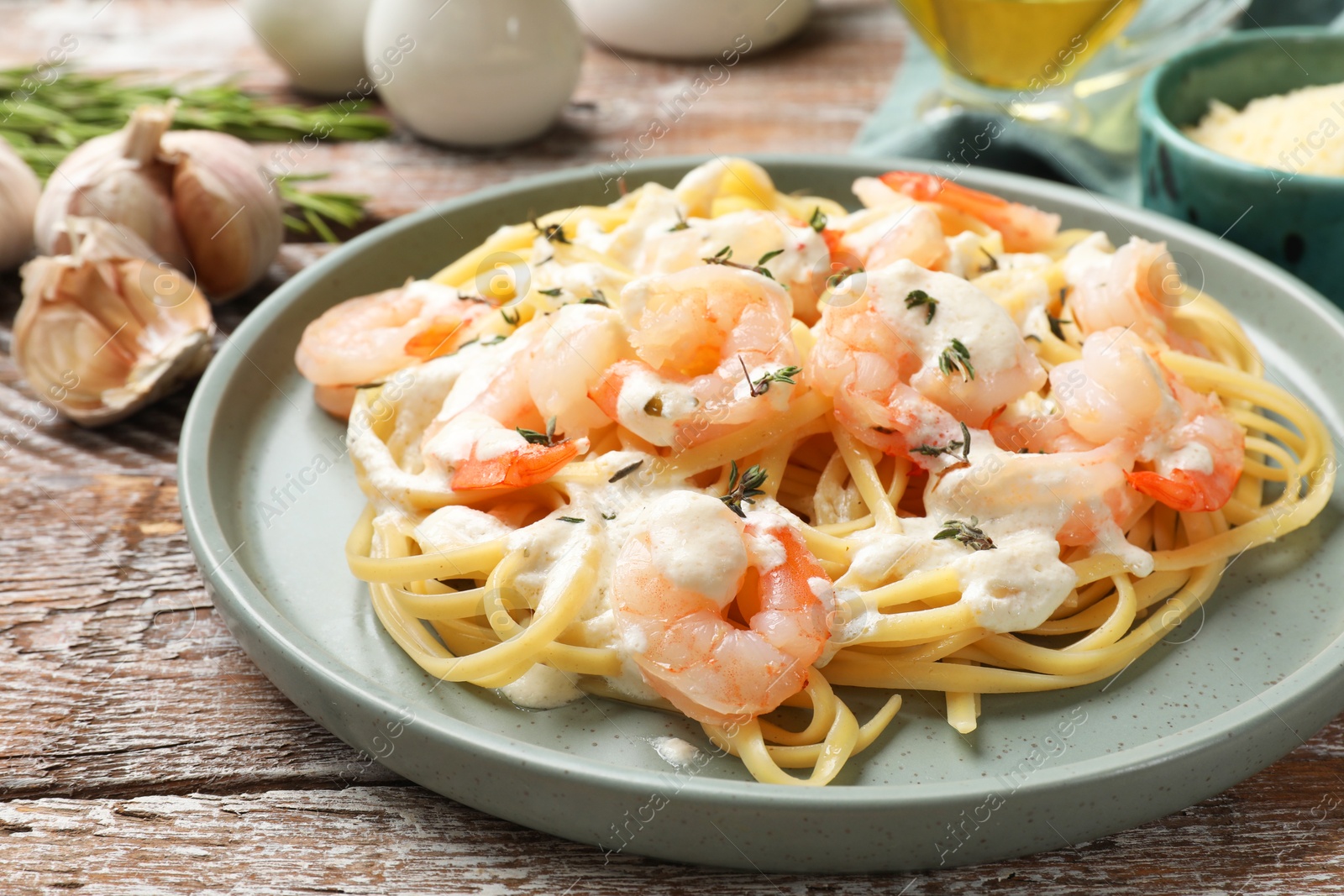 Photo of Delicious pasta with shrimps served on wooden table, closeup