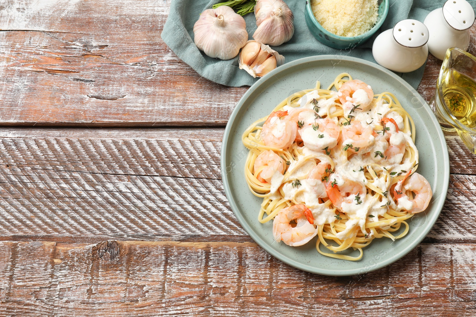 Photo of Delicious pasta with shrimps served on wooden table, flat lay. Space for text