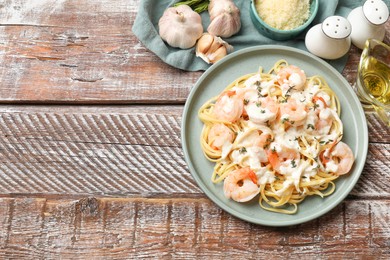 Delicious pasta with shrimps served on wooden table, flat lay. Space for text