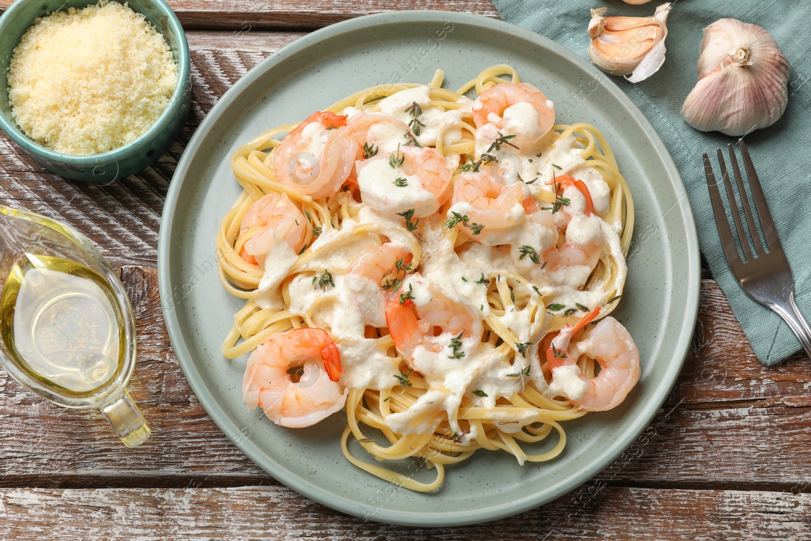 Photo of Delicious pasta with shrimps served on wooden table, flat lay