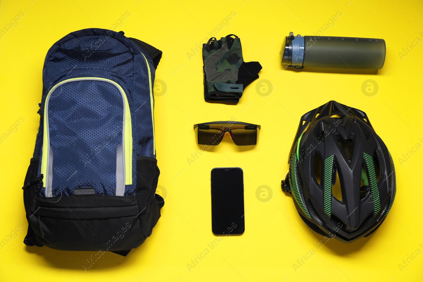 Photo of Flat lay composition with cycling accessories and smartphone on yellow background