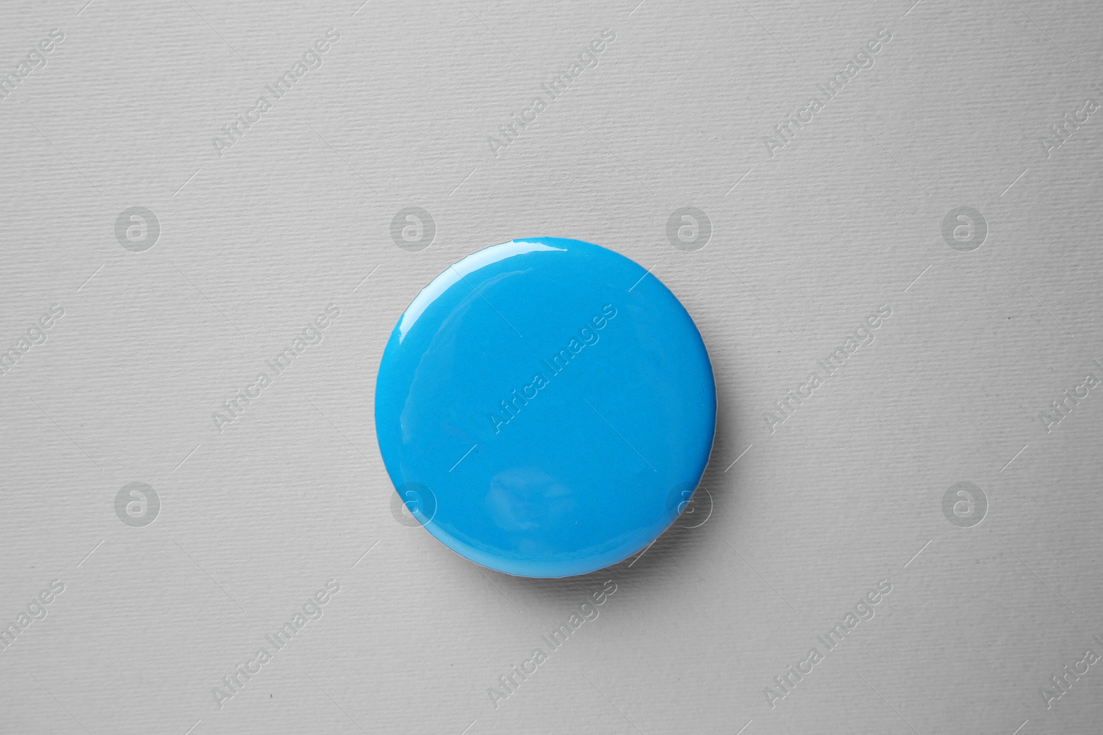 Photo of Blank light blue button badge on grey background, top view. Mockup for design