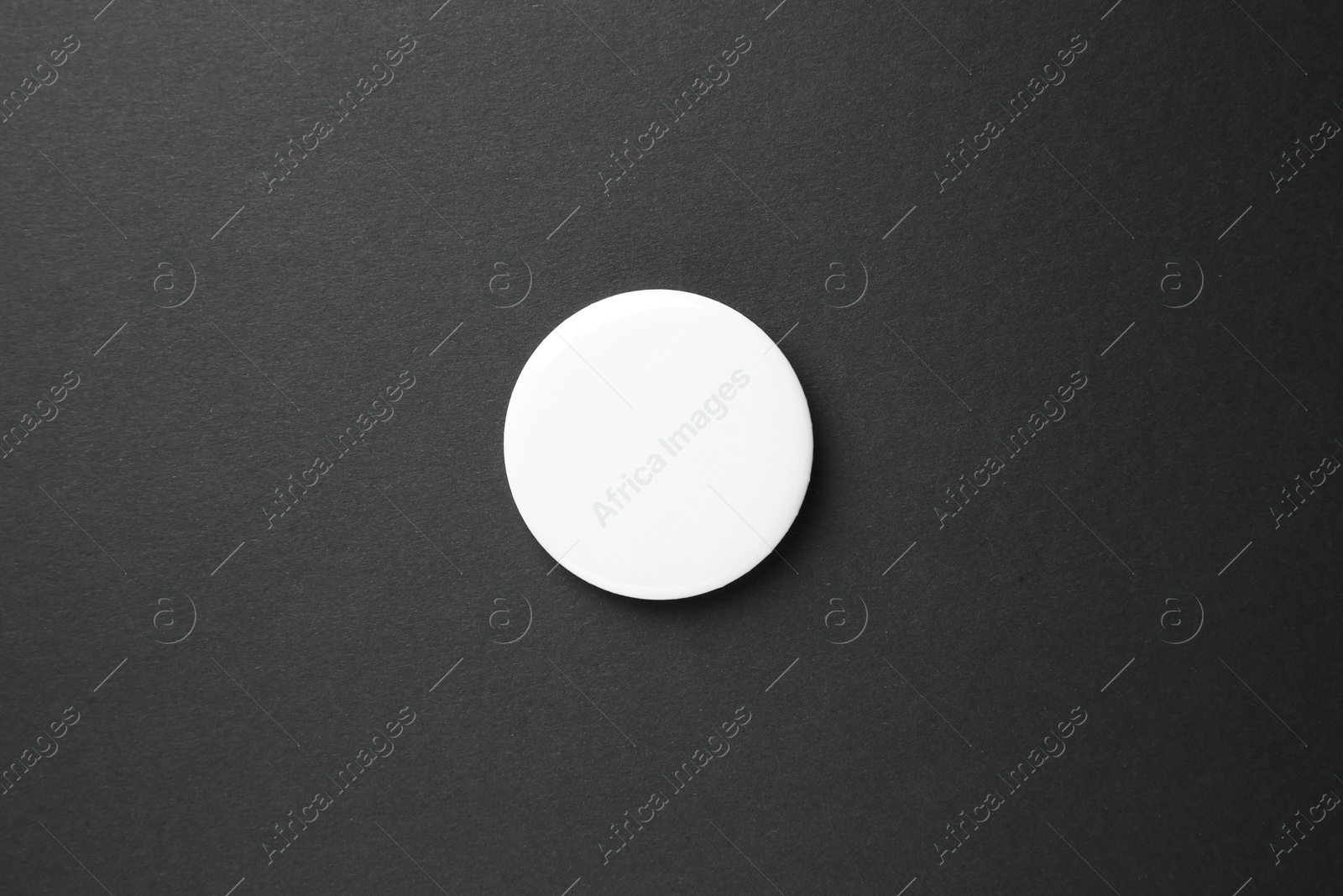 Photo of Blank white button badge on black background, top view. Mockup for design