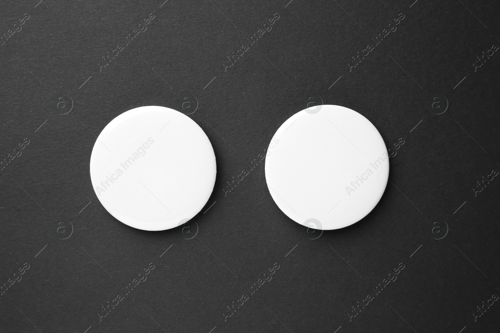 Photo of Blank white button badges on black background, top view. Mockup for design