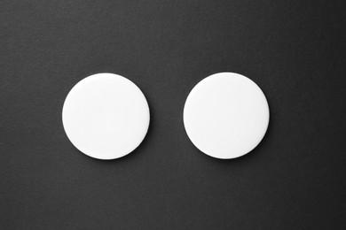 Photo of Blank white button badges on black background, top view. Mockup for design