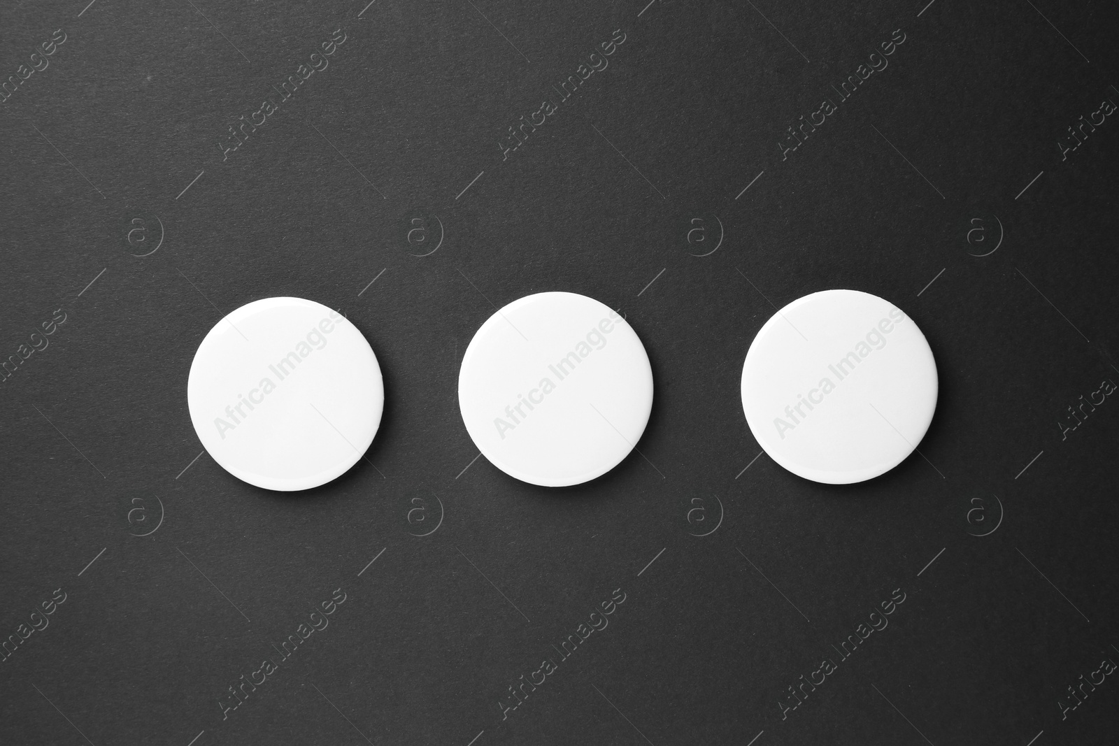 Photo of Blank white button badges on black background, top view. Mockup for design