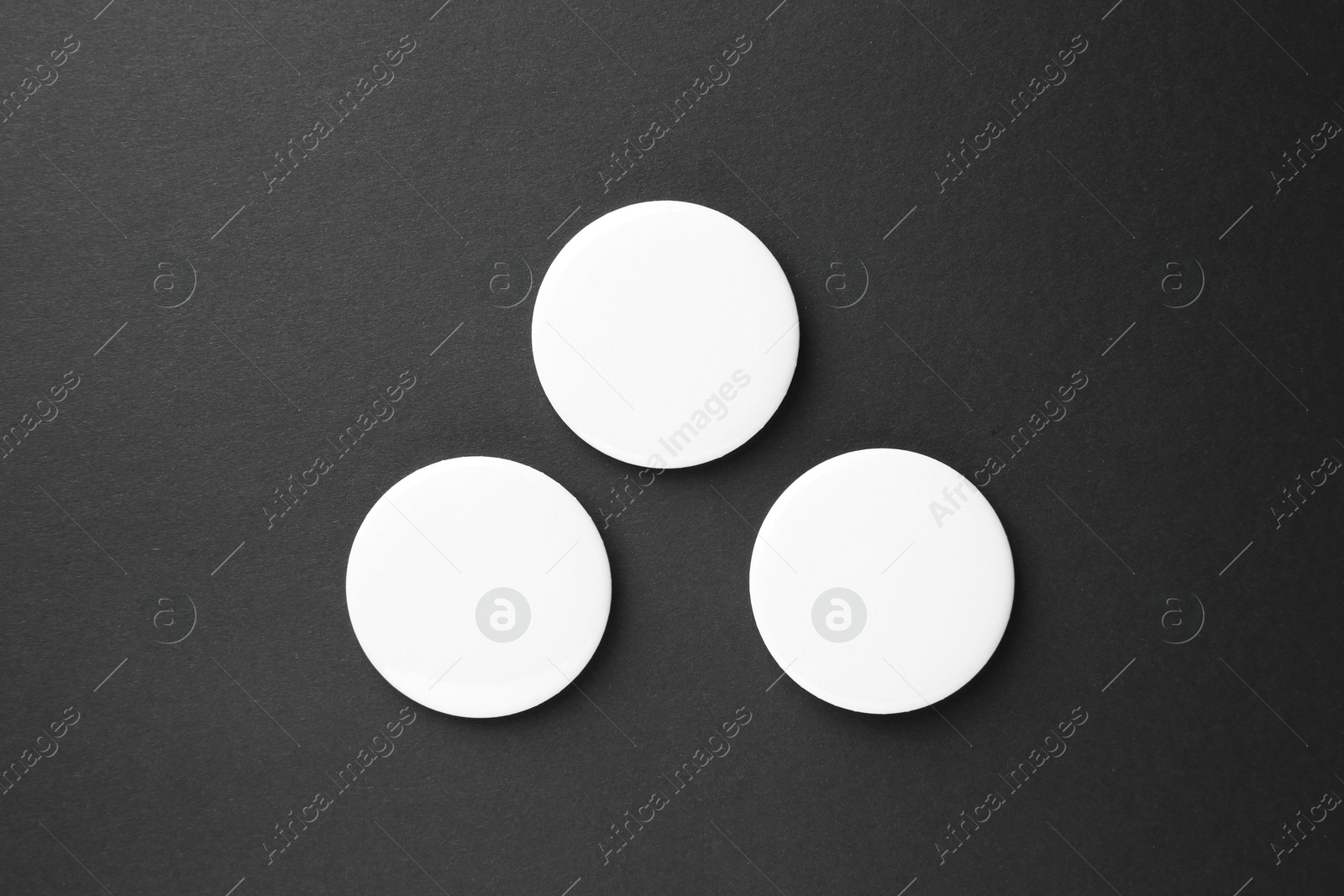 Photo of Blank white button badges on black background, top view. Mockup for design