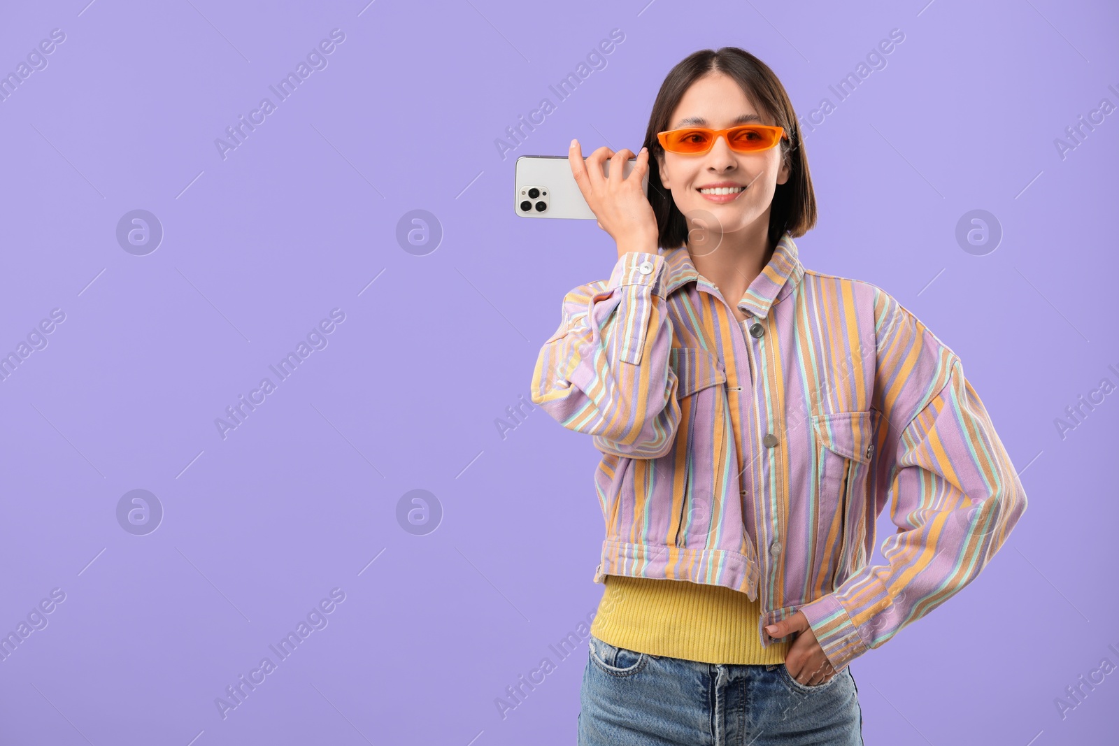 Photo of Beautiful woman in sunglasses with smartphone listening to voice message on violet background, space for text