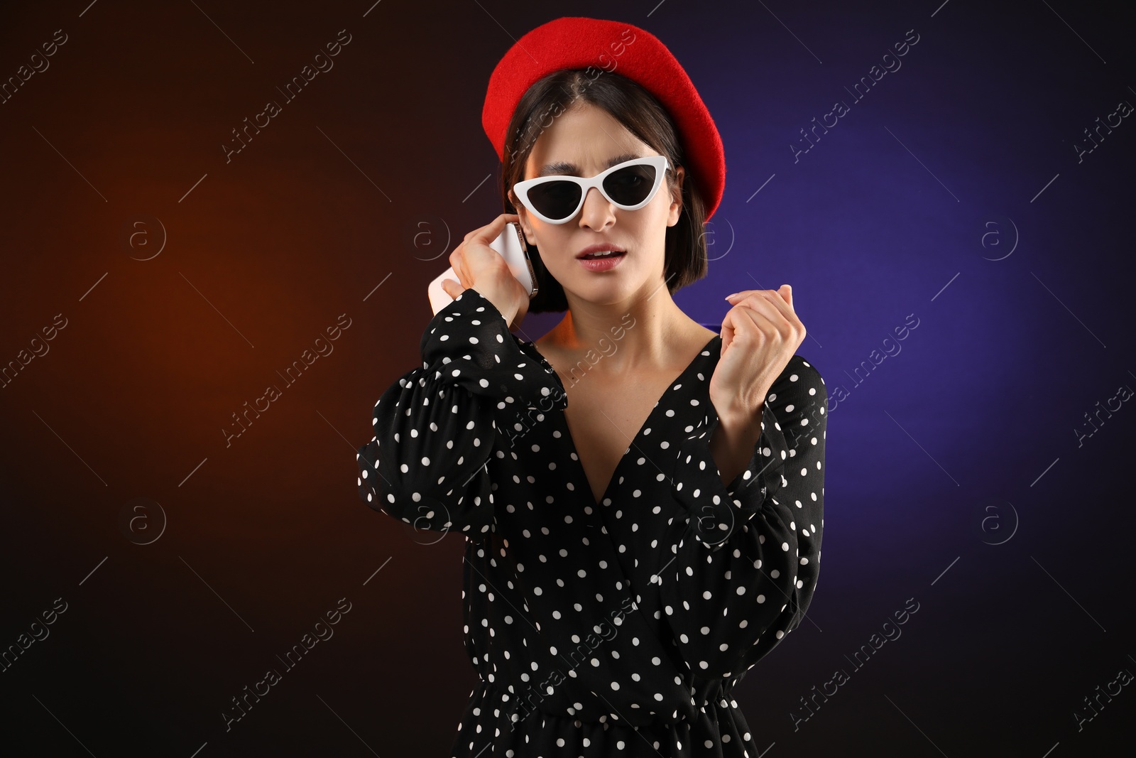 Photo of Stylish woman listening to voice message via smartphone on color background