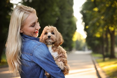 Beautiful young woman with cute dog in park, space for text