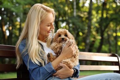 Photo of Beautiful young woman with cute dog on bench in park