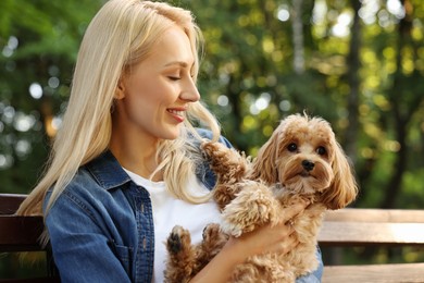 Beautiful young woman with cute dog on bench in park