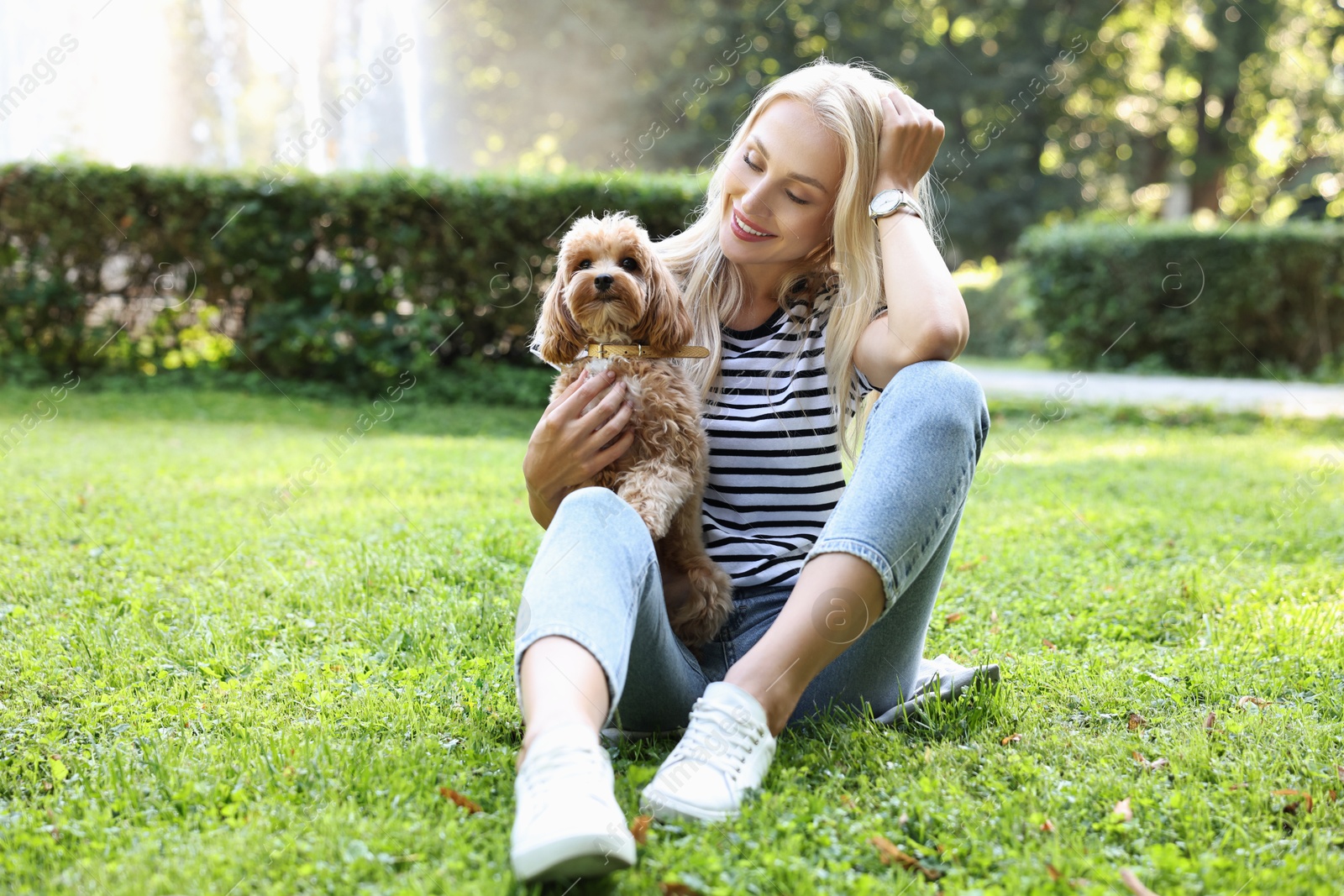 Photo of Beautiful young woman with cute dog on green grass in park