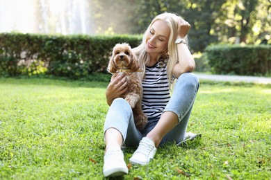 Beautiful young woman with cute dog on green grass in park