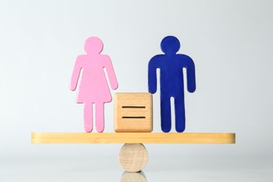 Gender equality concept. Male and female figures on scales against light background