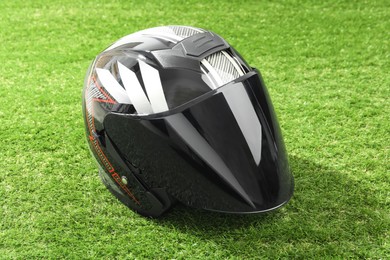 Modern motorcycle helmet with visor on green grass outdoors