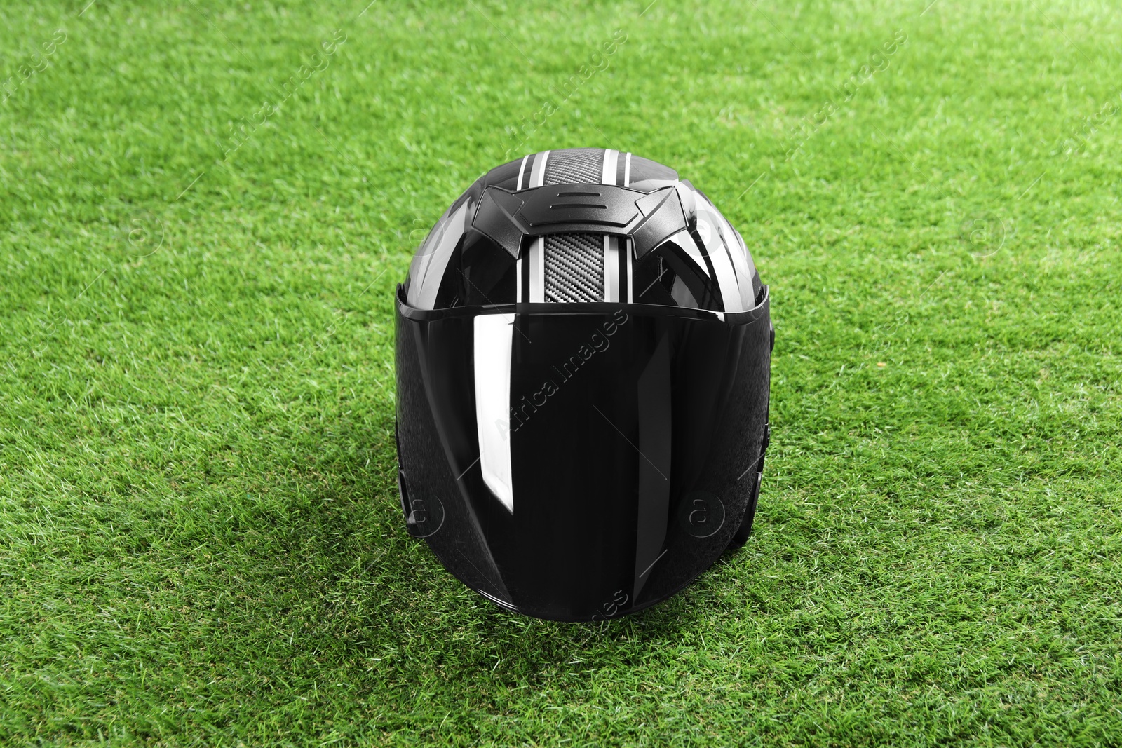 Photo of Modern motorcycle helmet with visor on green grass outdoors