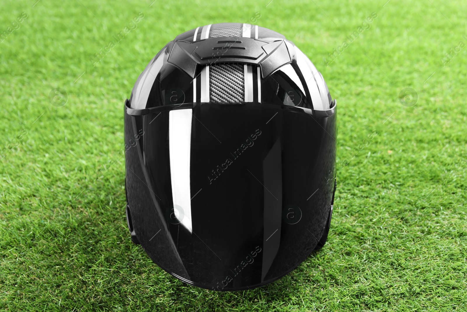 Photo of Modern motorcycle helmet with visor on green grass outdoors