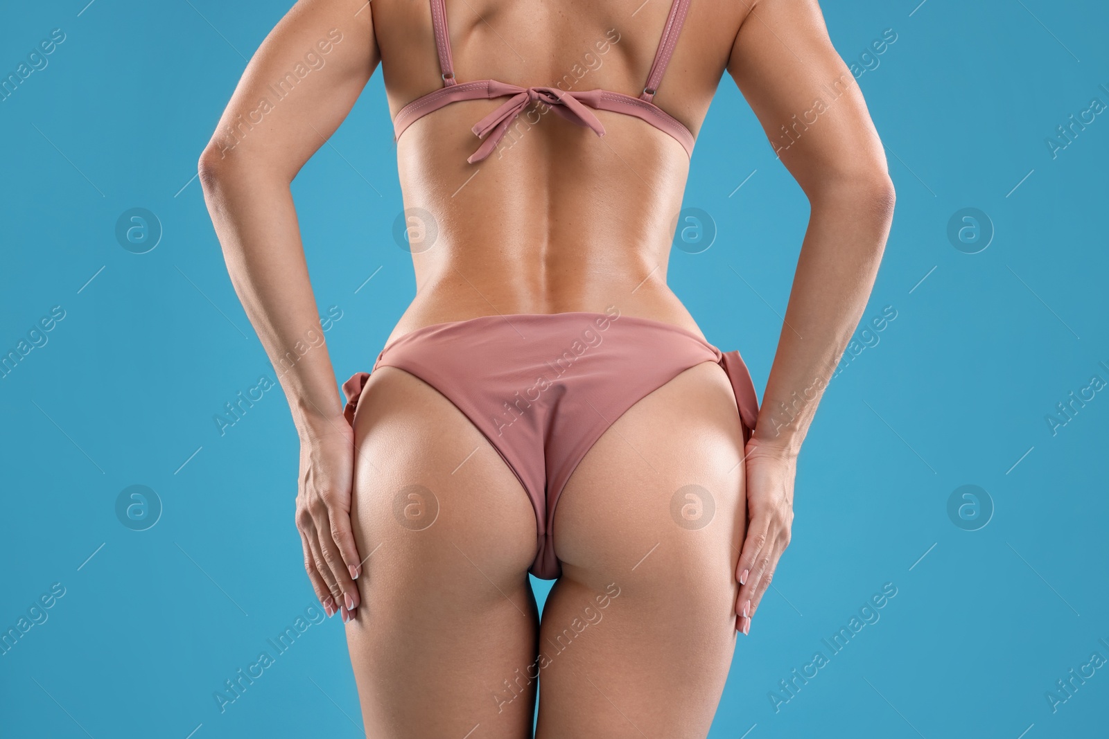 Photo of Woman in bikini on light blue background, closeup