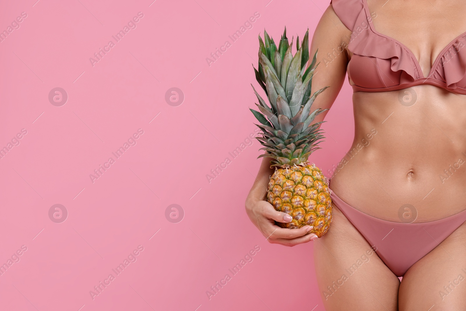 Photo of Woman in stylish bikini with fresh pineapple on pink background, closeup. Space for text