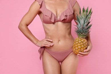 Woman in stylish bikini with fresh pineapple on pink background, closeup