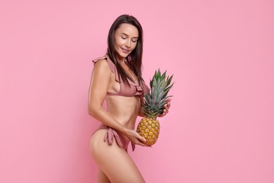 Photo of Woman in stylish bikini with fresh pineapple on pink background