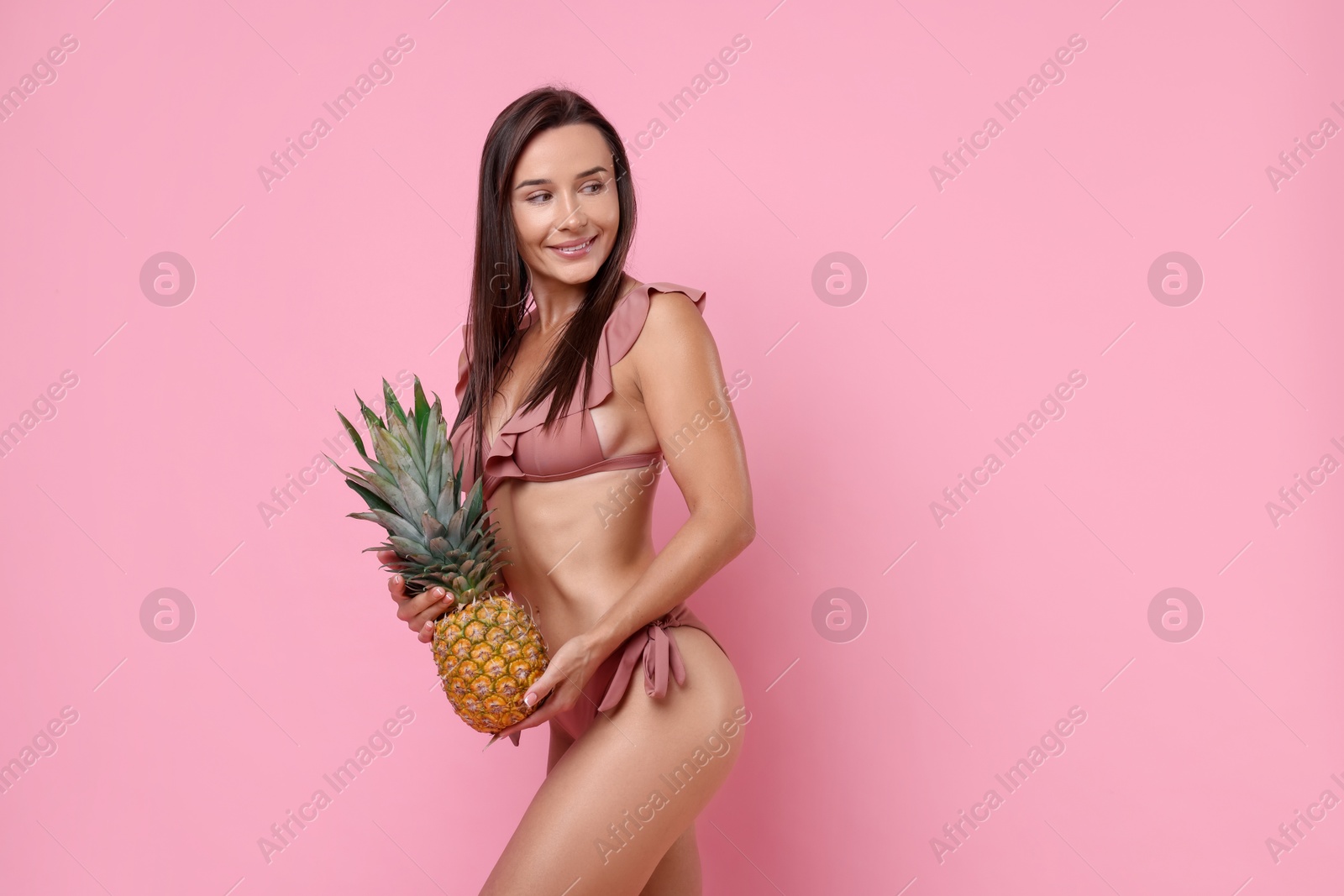 Photo of Woman in stylish bikini with fresh pineapple on pink background, space for text