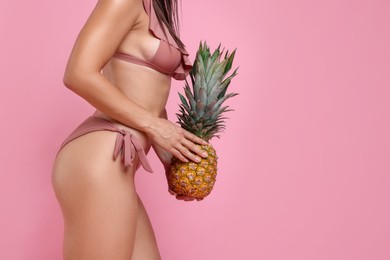 Woman in stylish bikini with fresh pineapple on pink background, closeup. Space for text