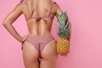 Photo of Woman in stylish bikini with fresh pineapple on pink background, closeup